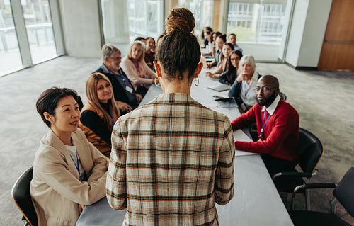 Female leading her team during a business training session with diverse professionals in a large boardroom setting