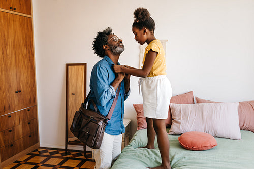 Caring daughter helping her dad look presentable before leaving home for work
