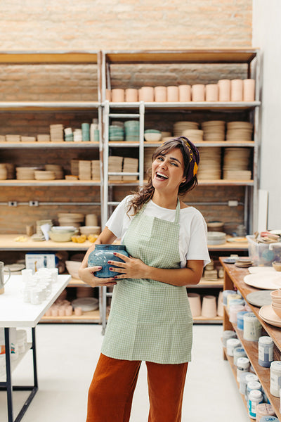 Successful female ceramist holding a handmade ceramic bowl in her shop