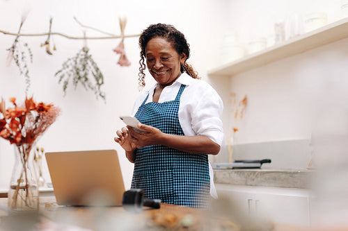 Black small business owner using a cellphone to connect with clients for her flower shop