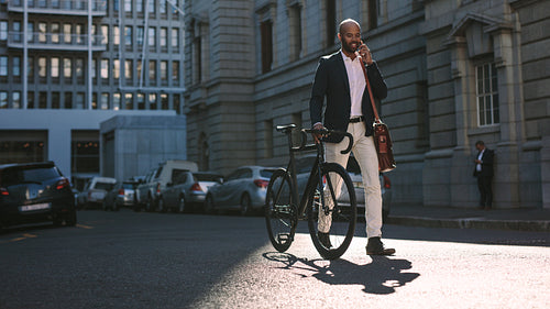 Businessman going to office by bicycle and talking on phone