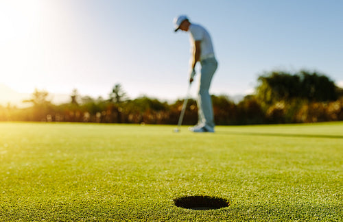Golf player putting ball in hole