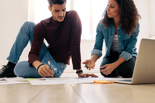 Business colleagues sitting on the floor and discussing work with business papers spread on the floor