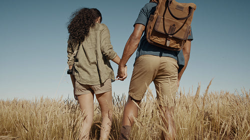 Couple hiking through dry grass on a mountain