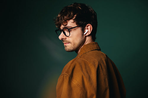 Technology shapes the man wearing earbuds and glasses in studio