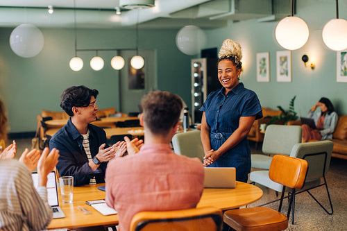 Smiling black woman stands confidently during a friendly team meeting