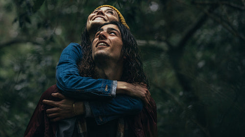 Couple at forest piggybacking in rain
