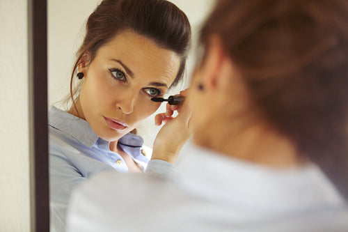 Businesswoman applying mascara 