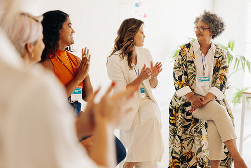 Cheerful businesswomen applauding their colleague during a confe