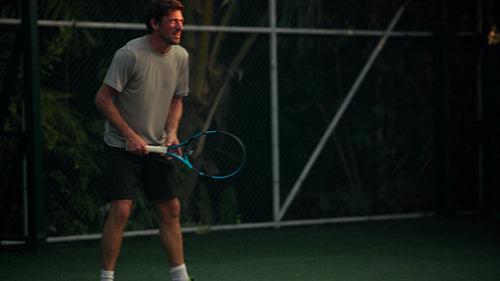 An athletic man plays an active game of tennis on an outdoor court, demonstrating fitness and skill