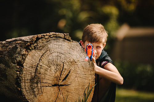 Boy playing with toy gun in playground.