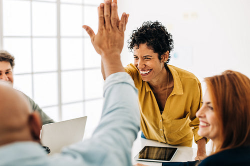 Colleagues doing a high five in an office