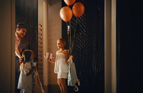 Resort staff interacting with friendly children holding balloons and a gift at a villa