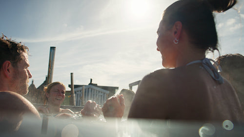 Friends high-fiving in a steaming outdoor hot tub during a social spa celebration