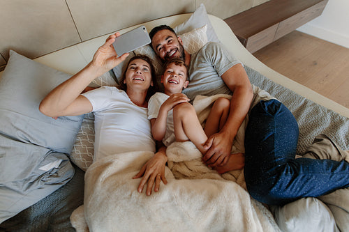 Family taking selfie on bed at home
