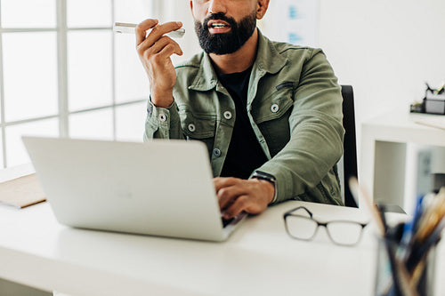 Male software developer talking on the phone at his desk