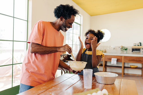 Family fun and laughter in the kitchen: Father and daughter making a cake together