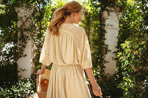 Smiling tourist woman walking along a plant tunnel
