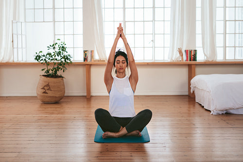 Beautiful young woman relaxing at home in yoga position