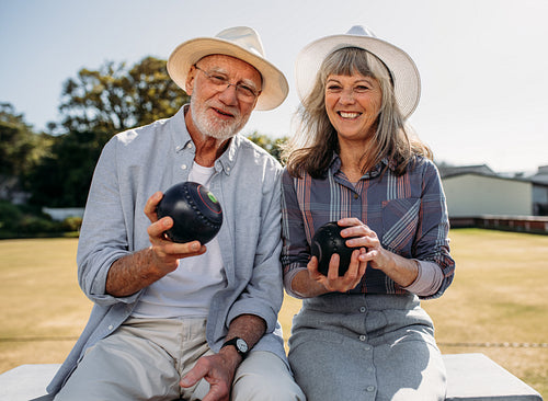 Senior couple sitting in a  park holding boules