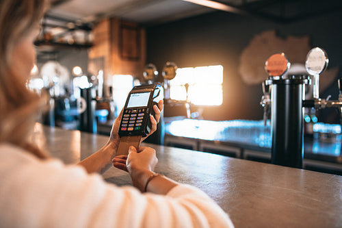 Woman paying bill using a credit card at bar