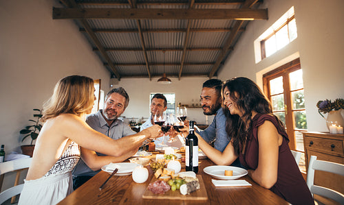 Friends having fun with wine and food at home party