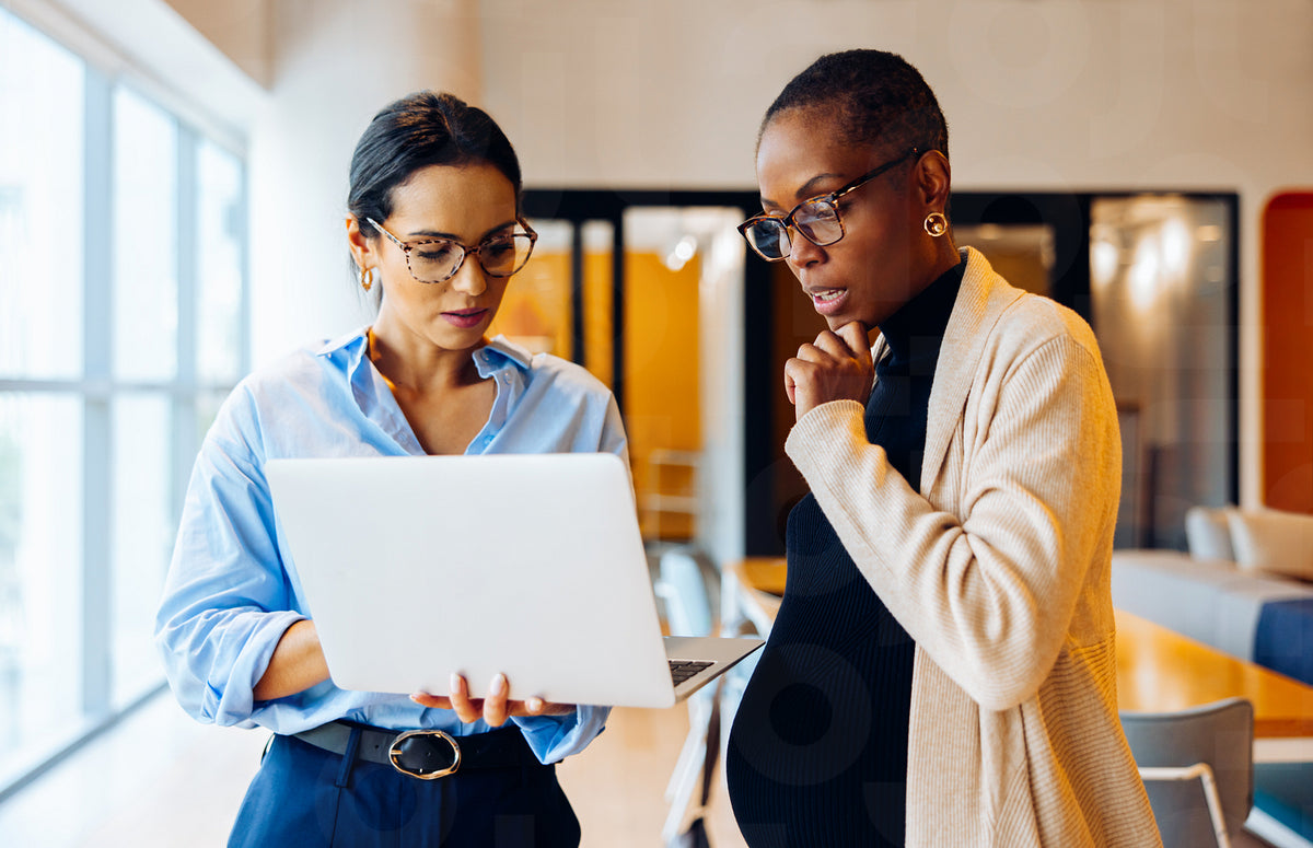 Two professionals working together discussing information on a laptop ...