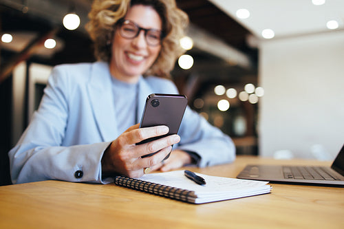 Business woman reading a text message on a mobile phone. Woman working in a coworking office