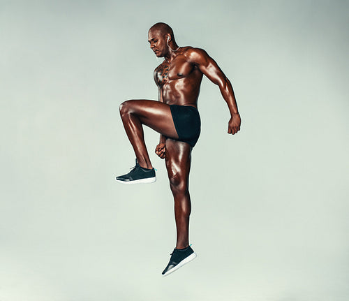 Fitness man jumping and stretching over grey background