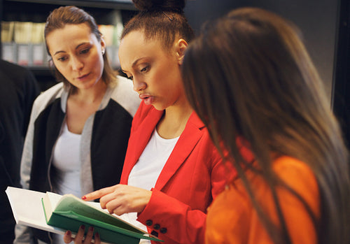 Young people in library looking at a book together