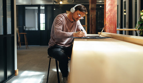 Professional web designer writing his progress in a clipboard