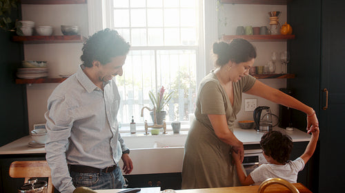 Fun family moments in the kitchen: Mom and dad dancing with their son at home