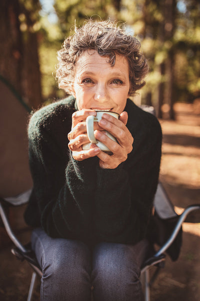 Mature caucasian woman having coffee at campsite