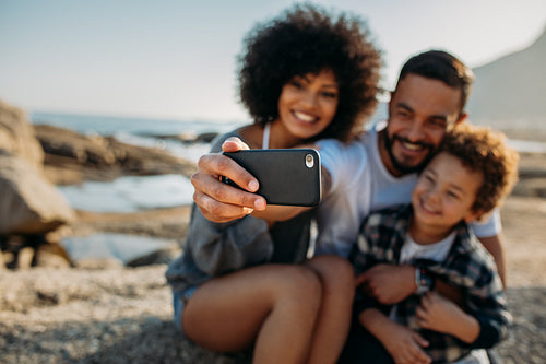 Man taking a selfie with his family sitting at the beach