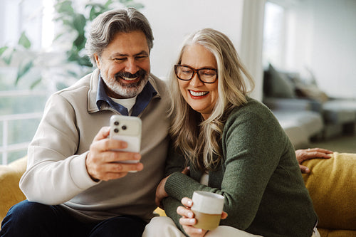 Senior couple use a smartphone together at home