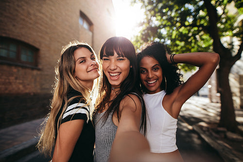 Young women having fun on city street and taking selfie