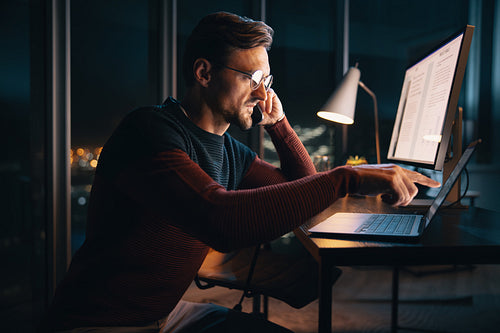 After hours communication: Young businessman balancing work life in the office