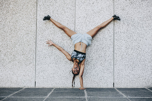 Fitness woman standing upside down on one hand
