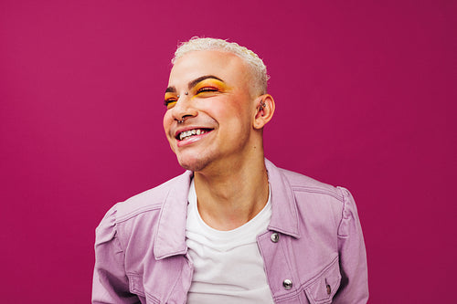 Queer man smiling cheerfully in a studio