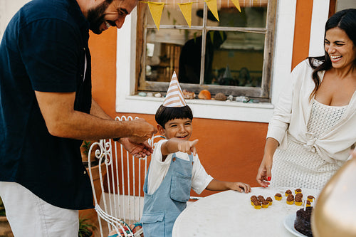 Family celebrating a child's birthday with a garden party and treats