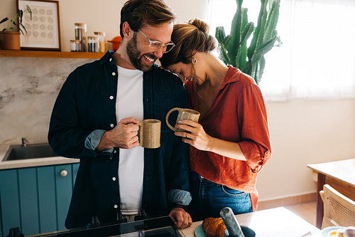 Couple sharing coffee and laughs in kitchen