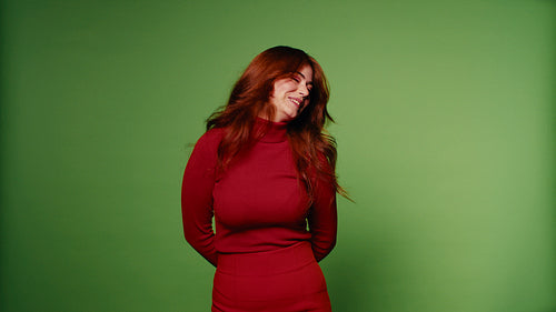 Happy woman in red clothes dances and shakes her hair on green screen