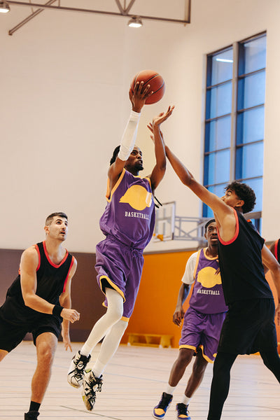 Men playing basketball indoors energetically