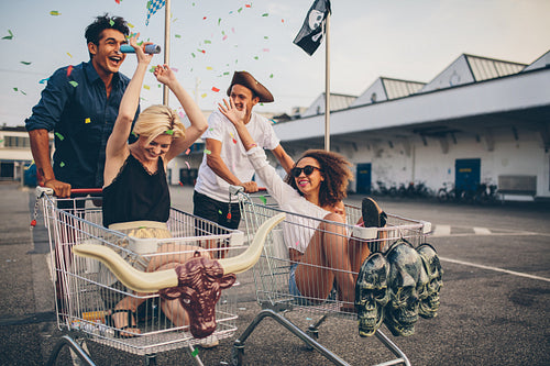 Young people racing with shopping cart and celebrating with confetti