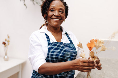 Creative florist holding a bouquet of dry flowers in her store