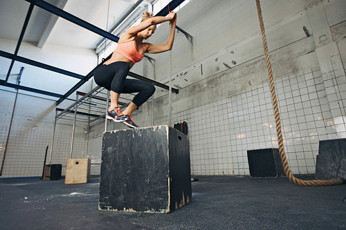Female athlete is performing box jumps at gym
