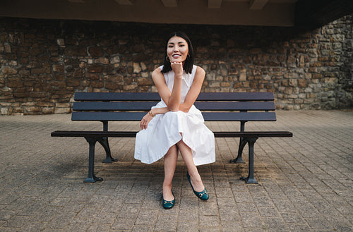 Young female student sitting on a bench outdoors