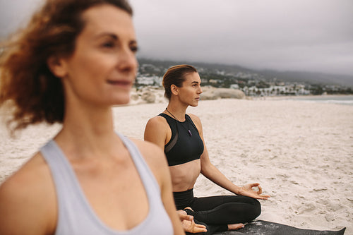 Women practicing yoga on the beach early in the morning