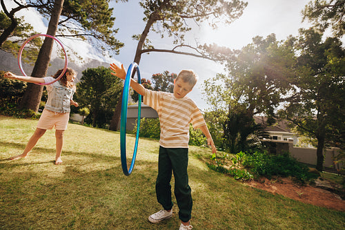 Children having fun outside playing with hula hoops on a sunny day