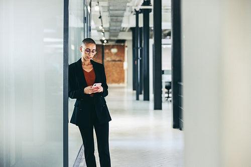 Confident businesswoman sending a text message in an office